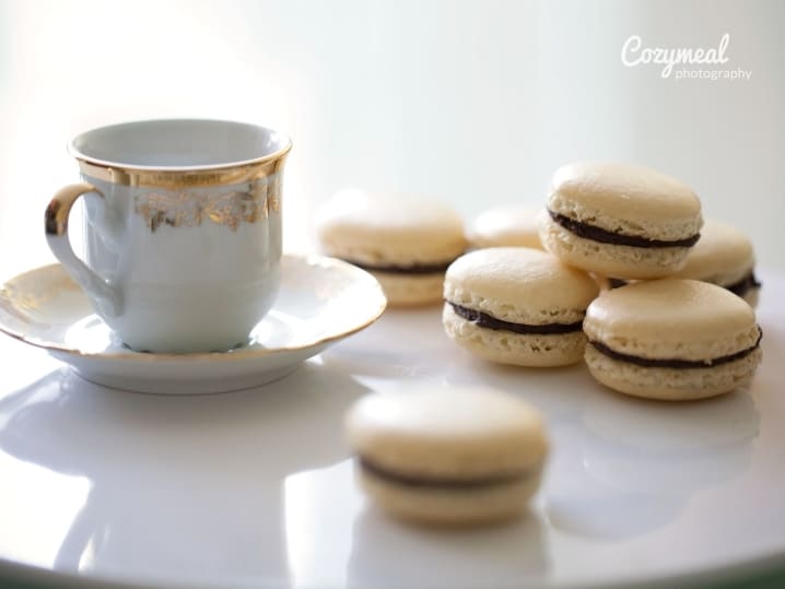 Stack of vanilla macarons with a cup of espresso on a white saucer.