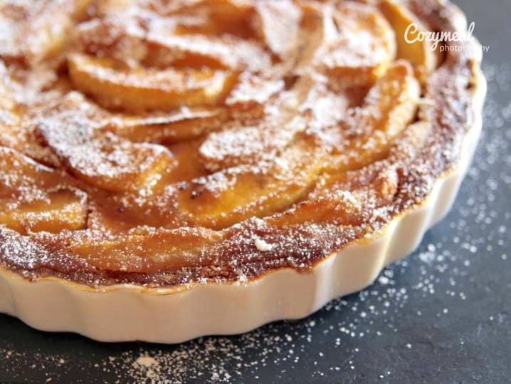 Baked caramel apple tartlet topped with thin apple slices and dusted with powdered sugar.