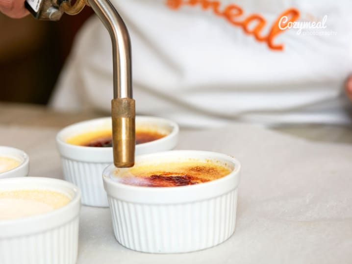 Hand torching the sugar topping on individual crÃ¨me brÃ»lÃ©e ramekins.