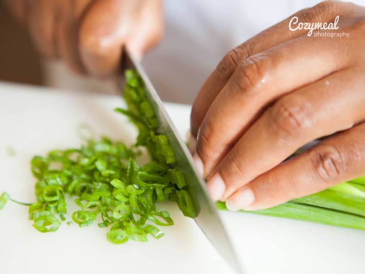 Slicing scallions on a cutting board.