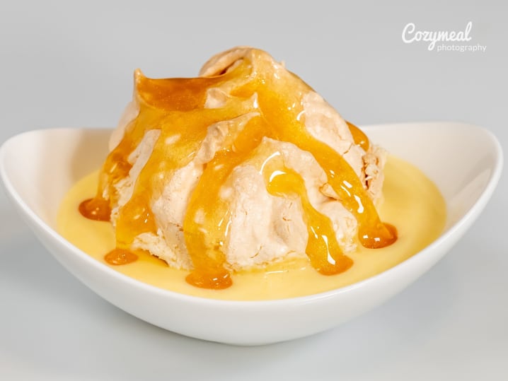 Peach dessert â€“ A scoop of vanilla ice cream topped with warm peach slices and caramel sauce, served in a white bowl.