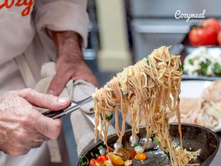 Hand assembling a lettuce wrap with beef and dipping sauce in the background.
