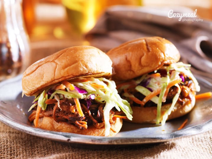 Carolina-style pulled pork sandwiches with slaw on soft buns, served with beer.