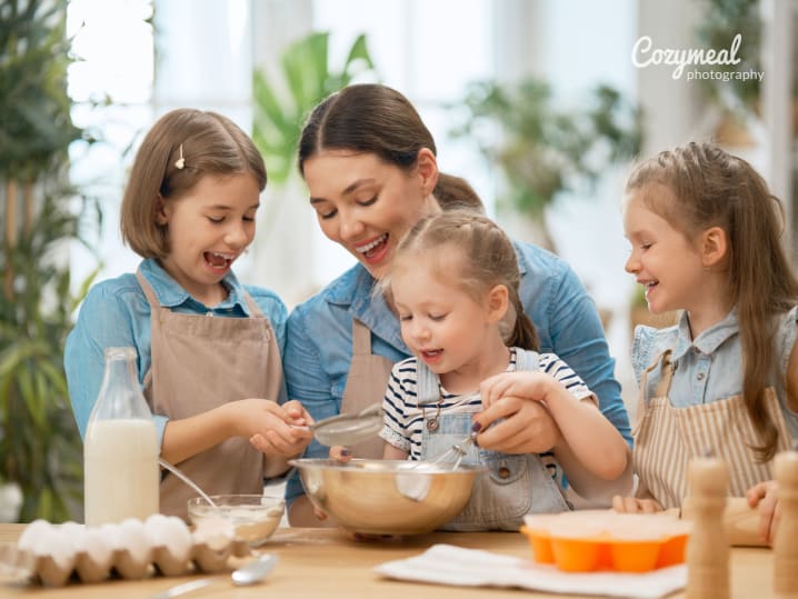 mother is baking with tree young daughters in the kitchen