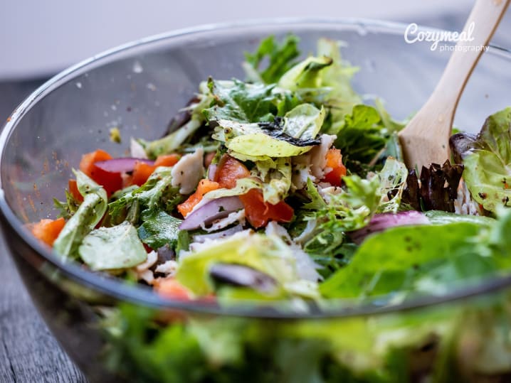 mixing Salade Verte with Tarragon-Dijon Vinaigrette in a glass bowl