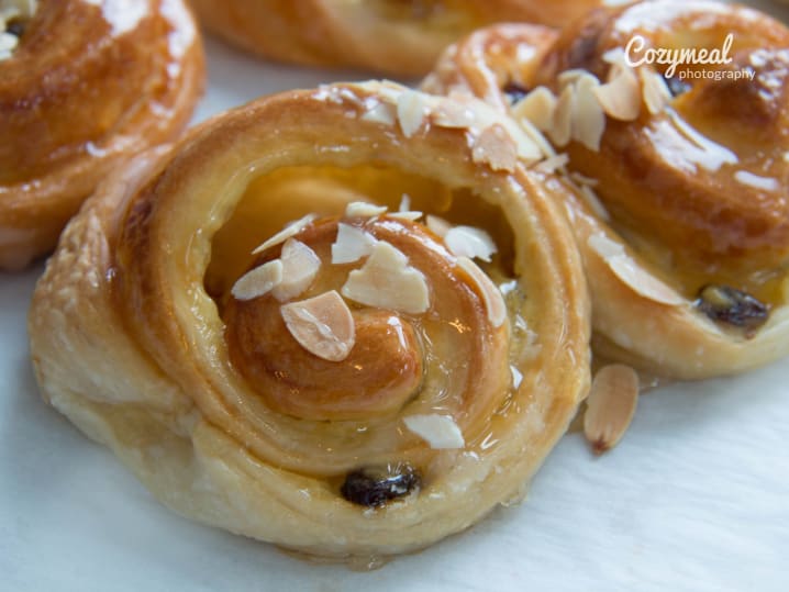 A close up of freshly baked Danish pastries topped with almonds and icing