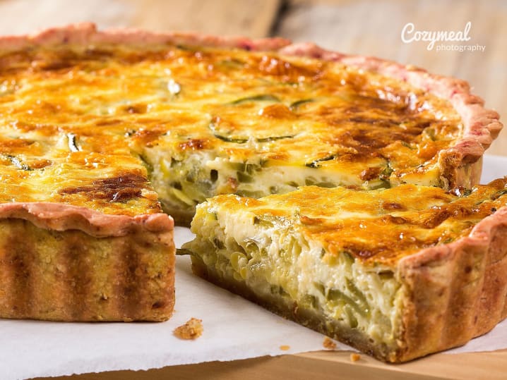 A freshly baked quiche with a golden crust, filled with cheese and herbs