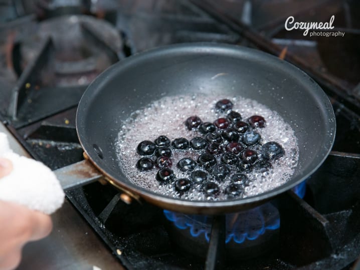 A frying pan with blueberries being cooked for a dessert sauce