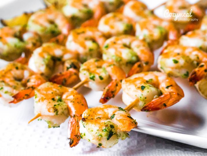 A platter of shrimp appetizers garnished with fresh herbs and lime slices