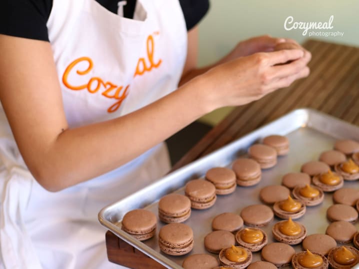 A tray of freshly baked macarons being prepared in a workshop