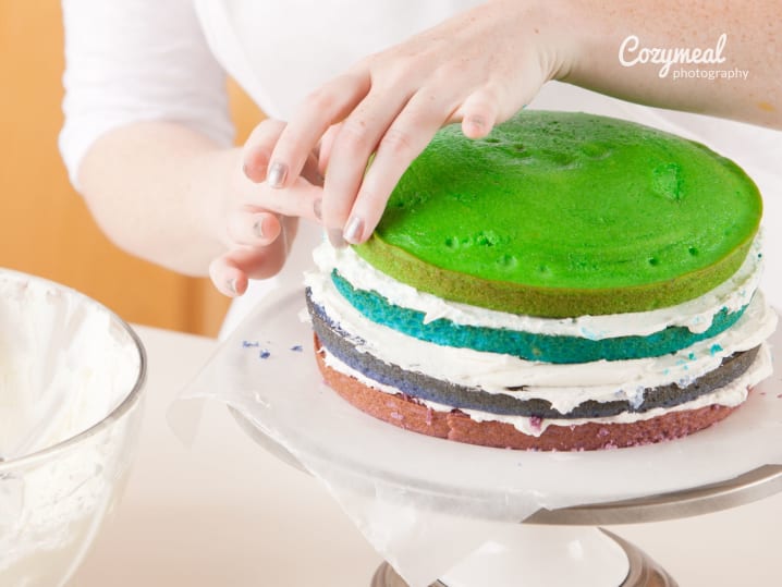 Adding colored sponge layers to assemble rainbow cake