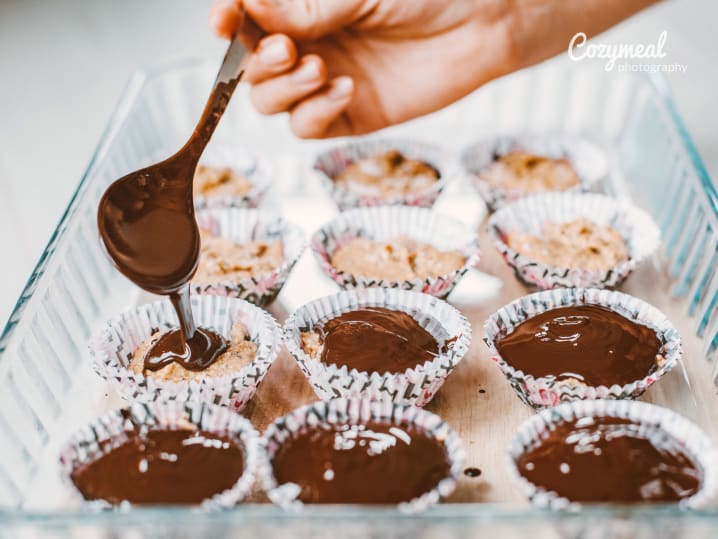 Chocolate glaze being poured onto cupcakes during a baking session
