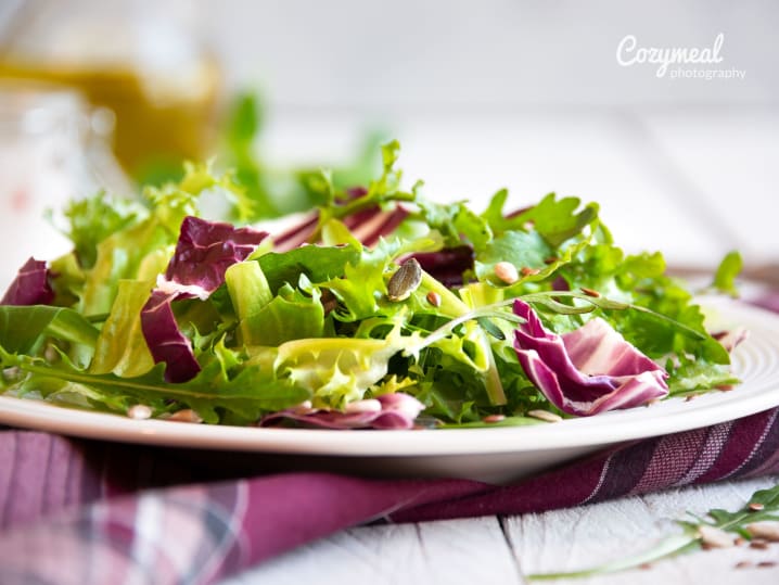 Fresh mixed greens salad â€“ A colorful salad with leafy greens, radicchio, and possibly beets or apples, on a white plate atop a purple napkin.