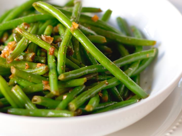 sautГ©ed green beans garnished with almonds served on plate