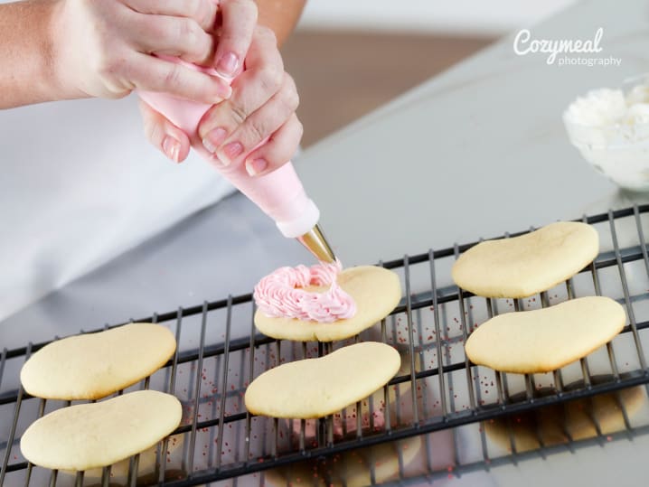 Icing freshly baked hear shaped cookies on a cooling tray