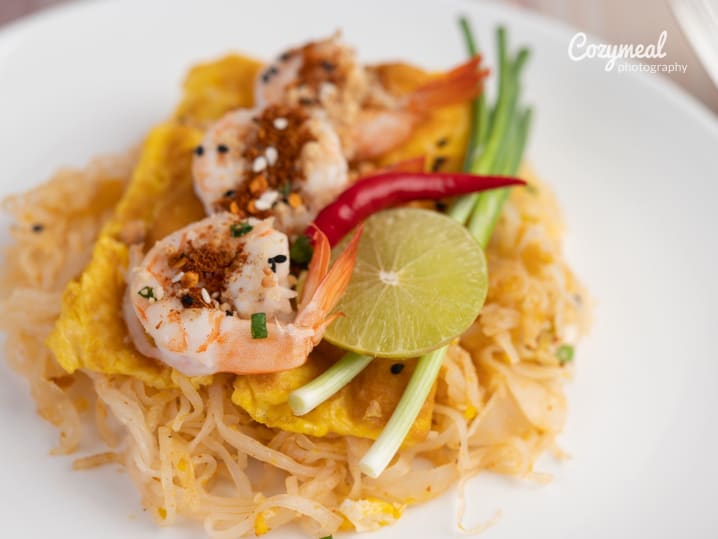 classic pad thai noodles topped with lime and crushed peanuts served on plate