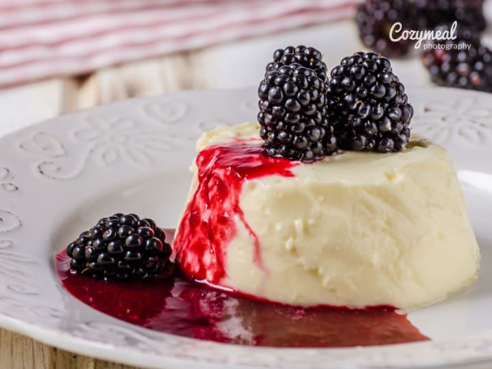 creamy panna cotta dessert topped with honey and fresh blackberries