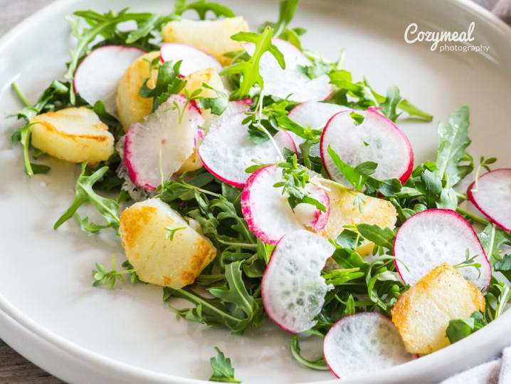 fresh radish and arugula salad garnished with microgreens served on white plate