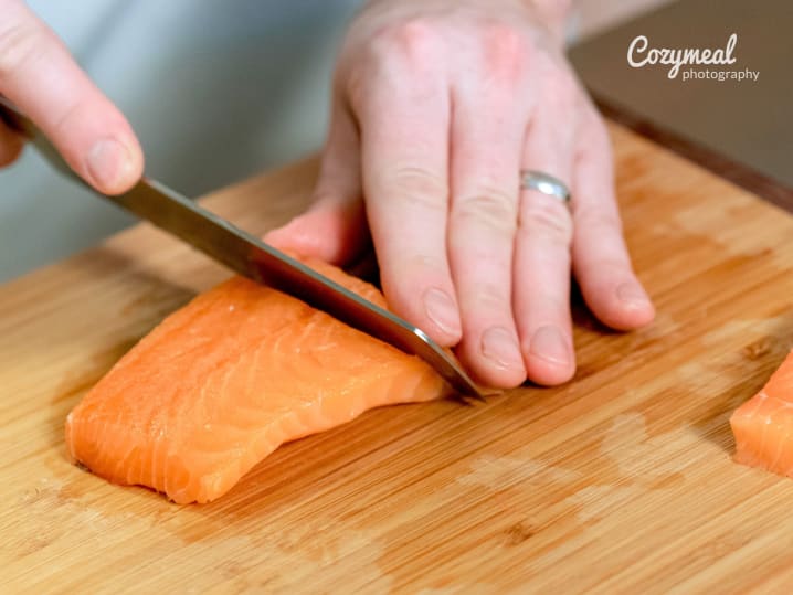 Salmon fillet being sliced on a cutting board