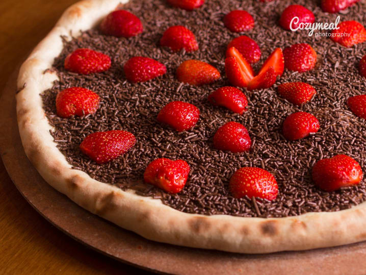 dessert pizza topped with fresh strawberries and chocolate sauce