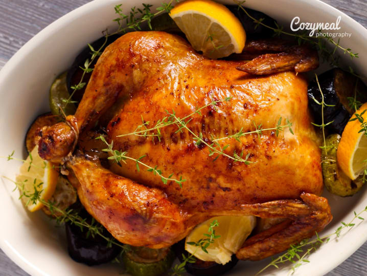 classic French roasted chicken garnished with herbs and lemon slices
