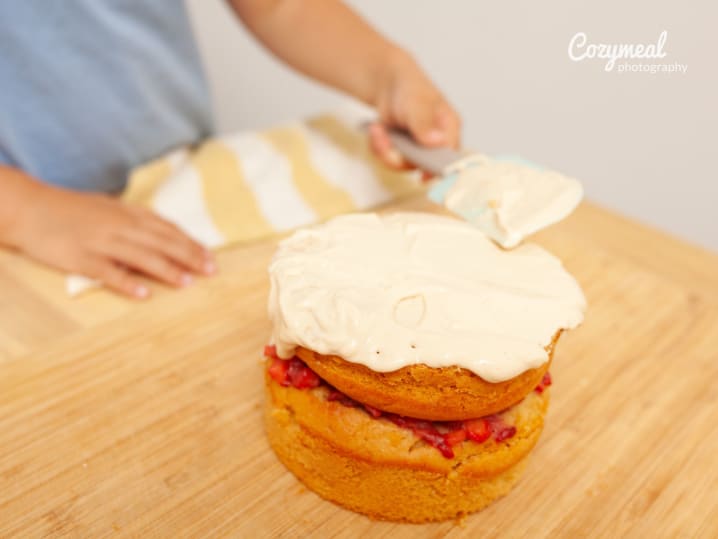 layering fresh berry cake with vanilla frosting