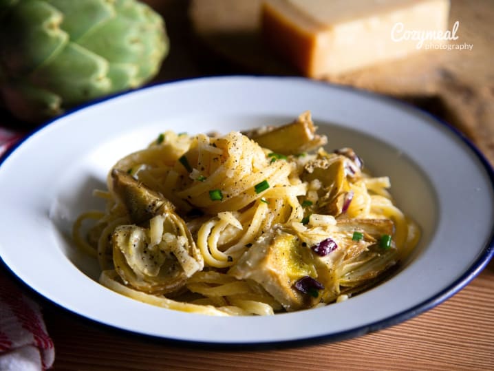 plated artichoke fettuccine pasta served on rustic wooden table