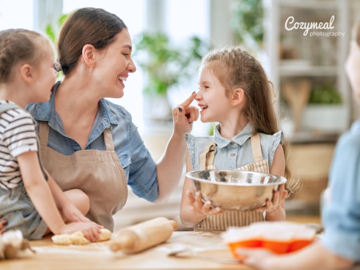 Family baking together in kitchen â€“ A smiling adult and two children baking at a kitchen table, sharing dough and laughter during a family-friendly activity.