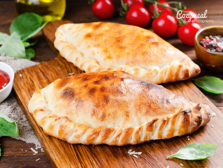 freshly baked calzone pizza served on wooden board