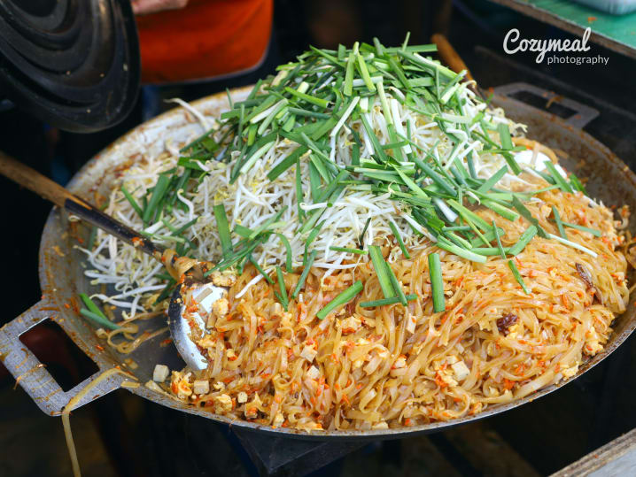 chef cooking pad thai in large skillet