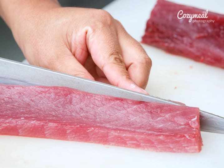 chef making sushi with sliced tuna