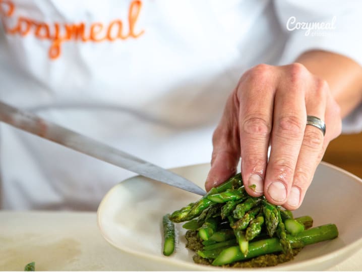 chef plating asparagus and green beans in a plate