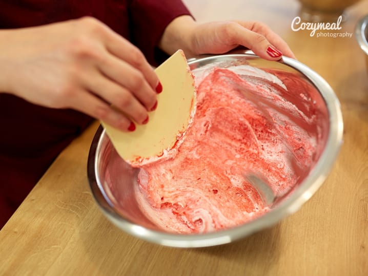 chef with spatula stirring macarons batter