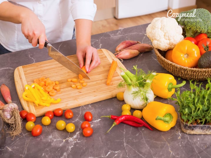 child cutting vegetables in the kitchen on a wooden board