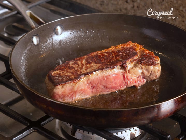 cooking and searing steak in a pan
