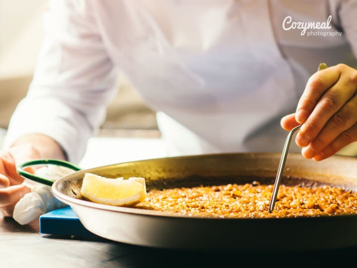 chef carefully cooking paella in large pan