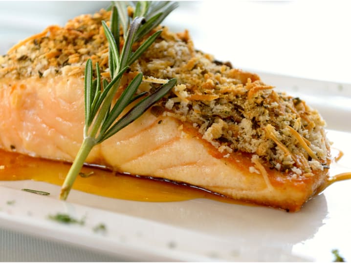 crusted salmon over sauce with rosemary sprig