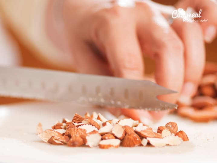 chef chopping almonds on wooden cutting board