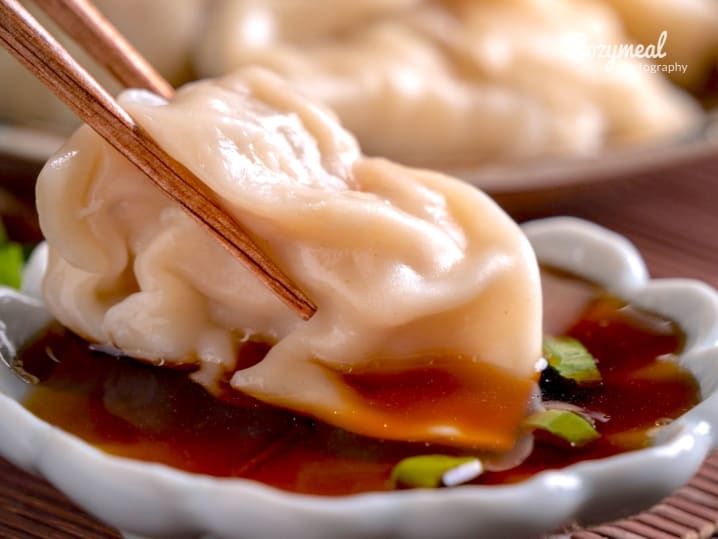 dipping steamed dumpling in sauce