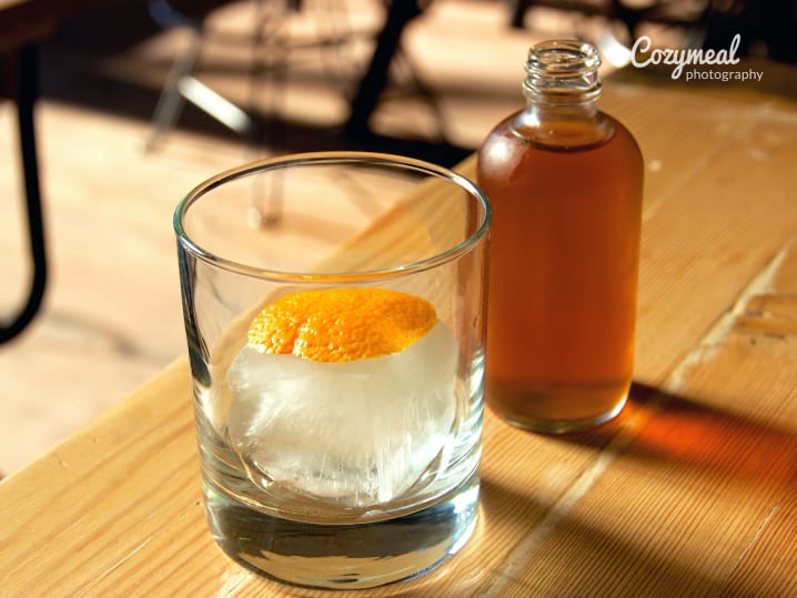 empty old fashioned cocktail next to bourbon bottle