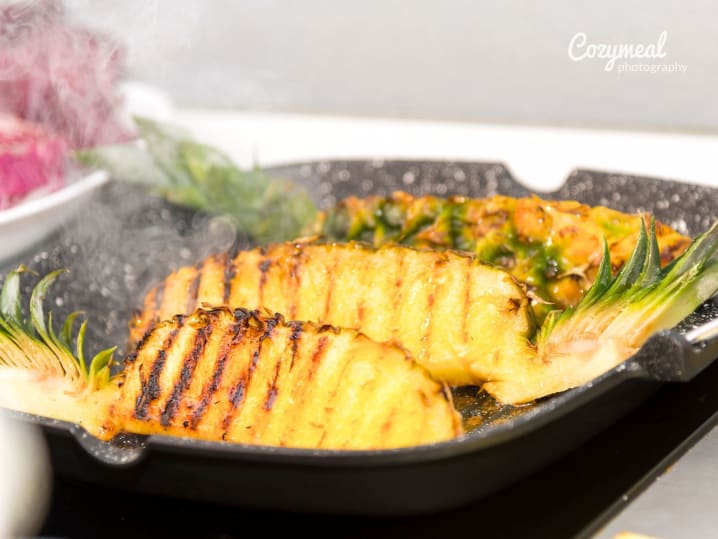fresh pineapple slices grilling on hot pan