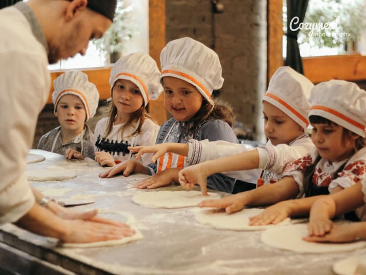 kids kneading pizza dough as Chef showcases them how to do it