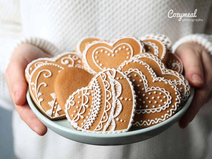 holding elegantly decorated heart cookies in a bowl