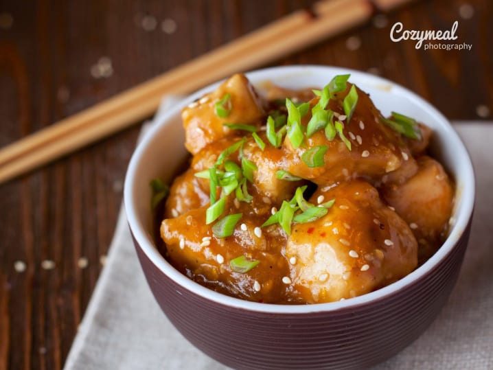 orange chicken in a bowl with chopsticks