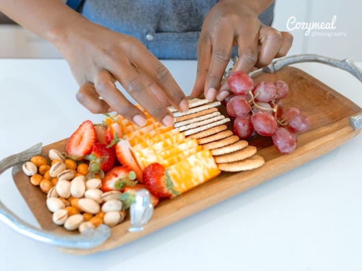 person arranging cheese and crackers on charcuterie board