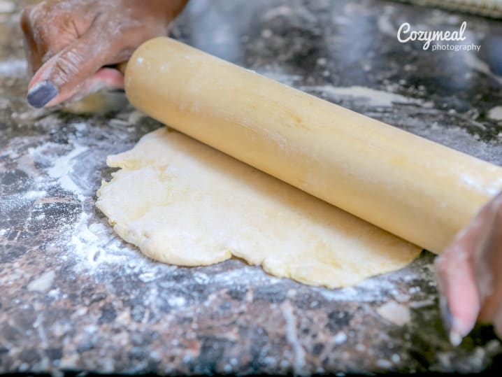 person rolling out donut dough