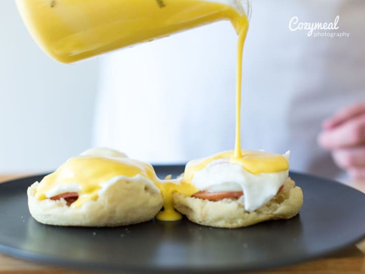 pouring Hollandaise sauce over eggs Benedict