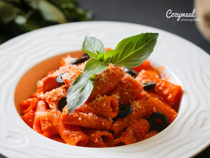 rigatoni pasta with aubergine and basil and Parmesan cheese garnish on a white plate