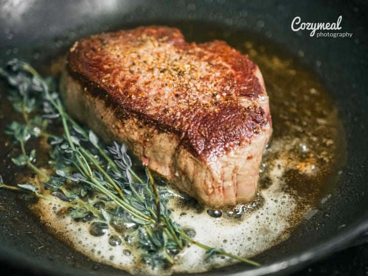 searing steak in a carbon steel pan