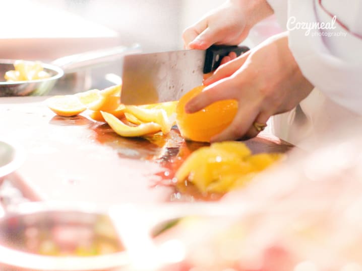close-up of chef segmenting fresh orange in kitchen